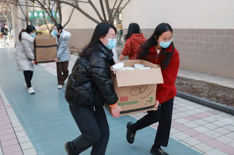 Volunteers carry food and supplies to students stuck in their dorms