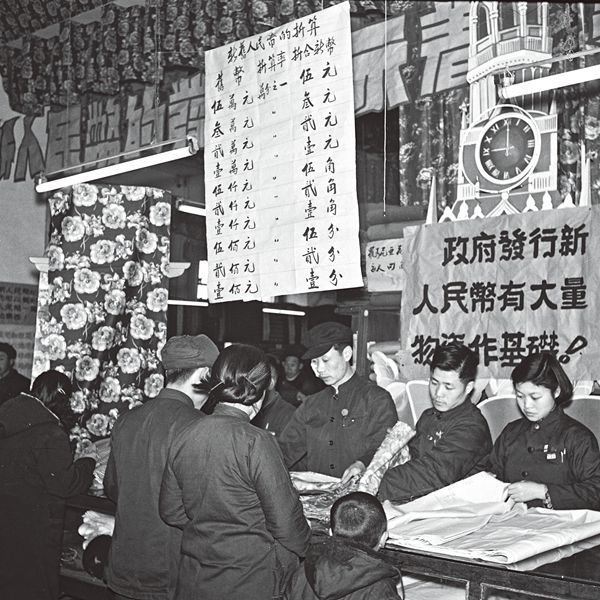 Chinese customers using renminbi notes to exchange for rolls of cloth at a shop in Beijing.