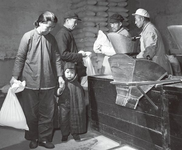 An older Tianjin women holding a child's hand after she used coupons to buy a bag of rice.