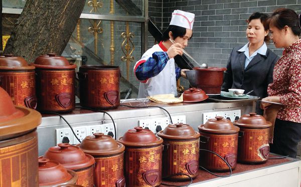 A cook serves medicinal soup to Chinese customers at a Cantonese restaurant.