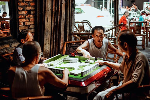 Four Chinese men going about a game of mahjong in a Sichuan teahouse. 