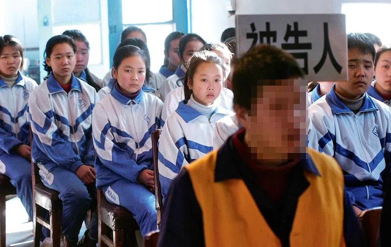 Young Chinese middle schoolers listen in on a juvenile offender's hearing, giving them a basic understanding of the law's process.