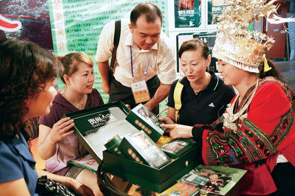 Chinese customers interact with a Miao women at an ethnic medicine conference in Guiyang. 