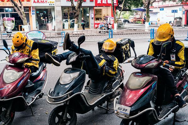 Chinese mei tuan delivery drivers take an afternoon nap on their scooters. 