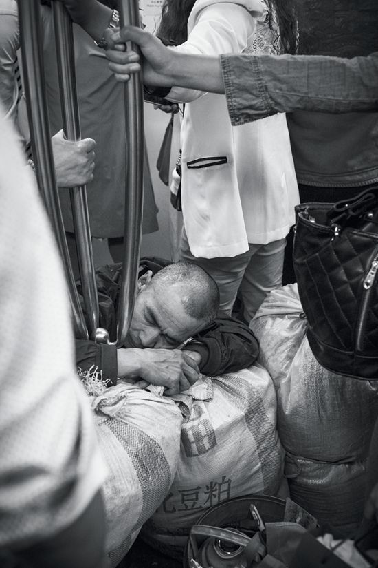 A Chinese man napping after a hard day's work while squatting on a bus.