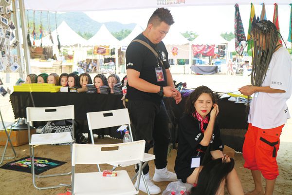 Chinese music festival attendee having her hair braided into dreadlocks.