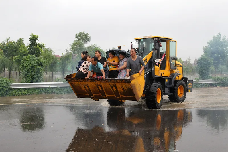 A yellow tractor carries residents away from heavy rain and floods in Zhengzhou (VCG)