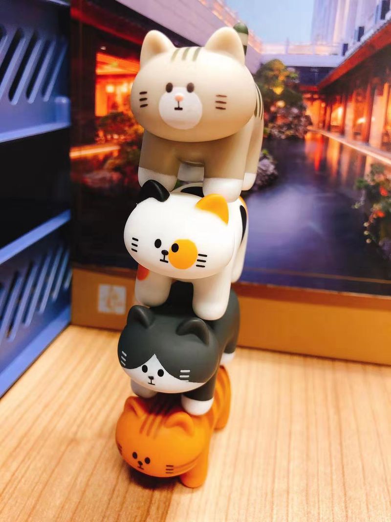 Four designer toy cats stacked on top of each other.