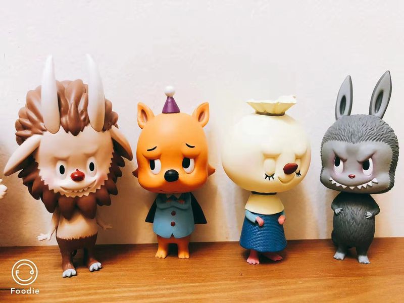 Four different Chinese designer cartoon toys propped up next to each other.