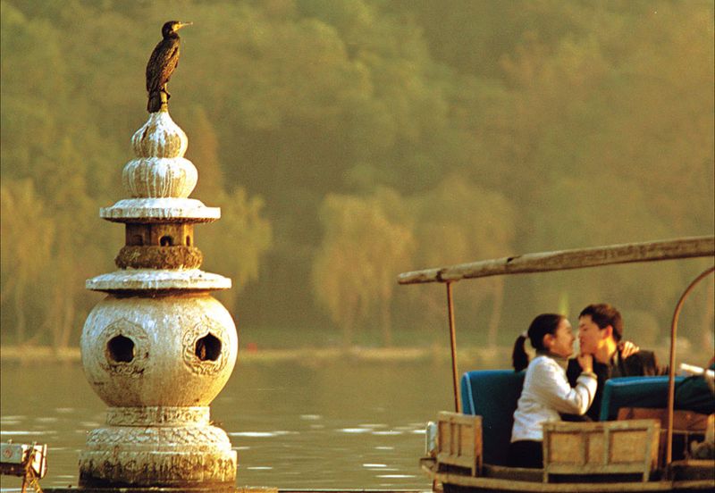 A cormorant rests on top of one of the three iconic stone pagodas of the Three Pools Mirroring the Moon in West Lake; cormorants are one of the most common birds in Hangzhou during the winter