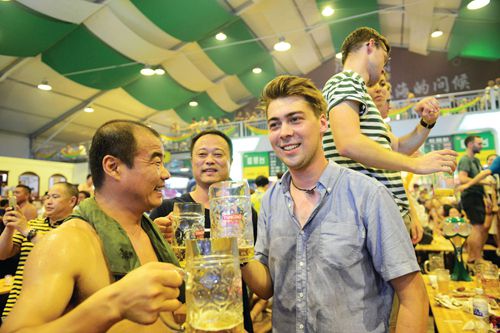 A local reveler enjoys a flagon of lager with a foreign visitor during the Qingdao Festival in 2017