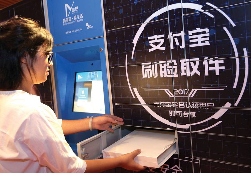 A Shanghai resident tests out a courier service pick-up locker with the latest facial recognition technology developed by Alibaba's Ant Financial in September 2017