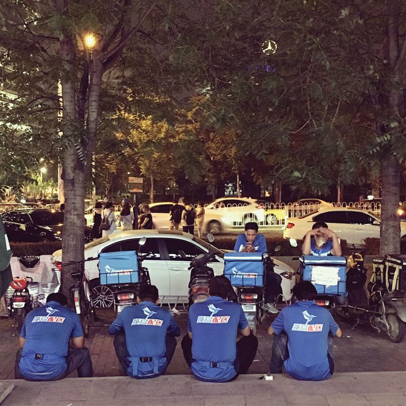 Down time: In the post-rush hour lull, Fengniao delivery men rest in Wangjing, Beijing, while checking their phones for new orders