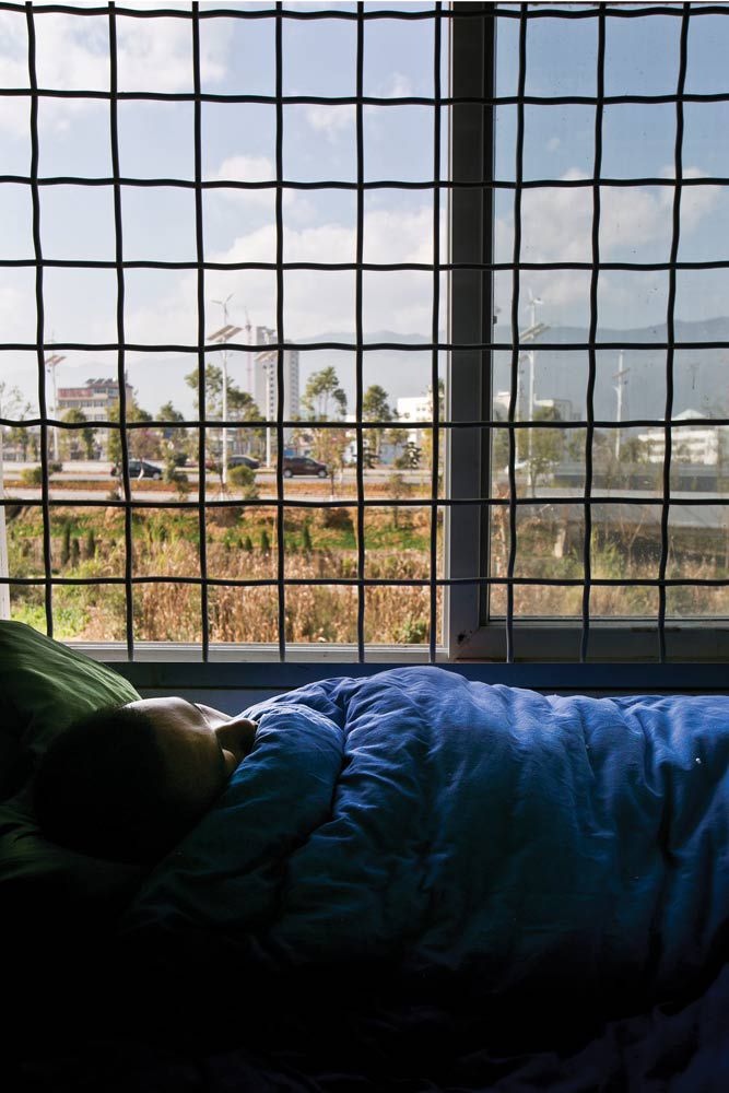 A patient resting at the Third People's Hospital in Lincang, Yunnan. Wires are installed in the ward to prevent escape.