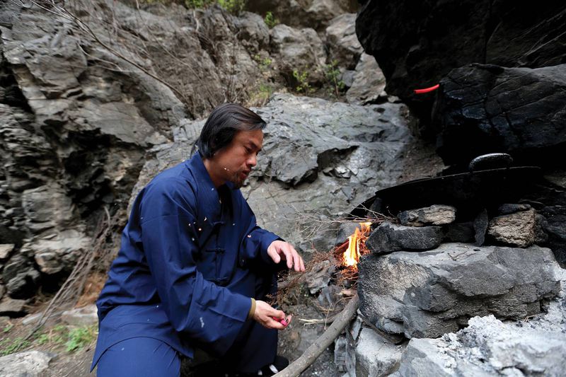A hermit cooking food outside his cave dwelling on Henan's Wangwu Mountain