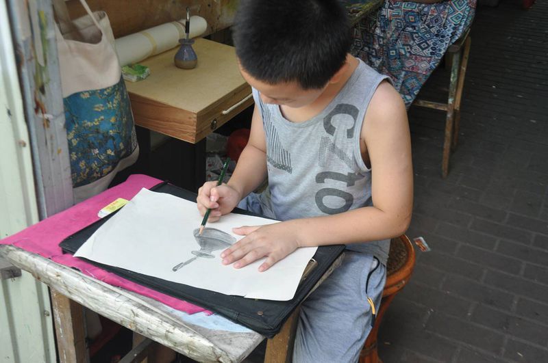 A shop owner's son sketches in front of the gallery