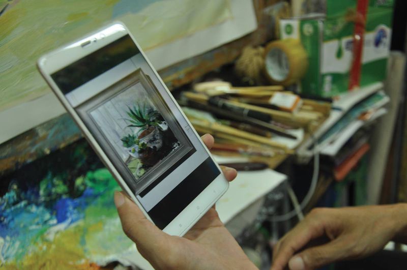Yang shows a painting on his phone that he just entered into a local competition